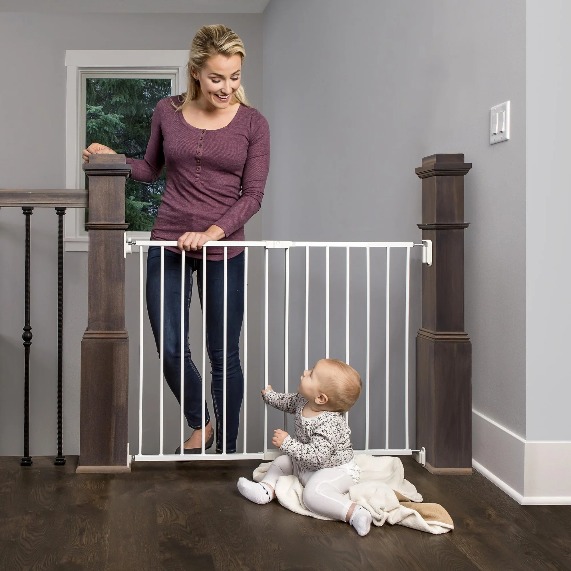Woman standing next to a baby gate with a child on the other side in a home setting.