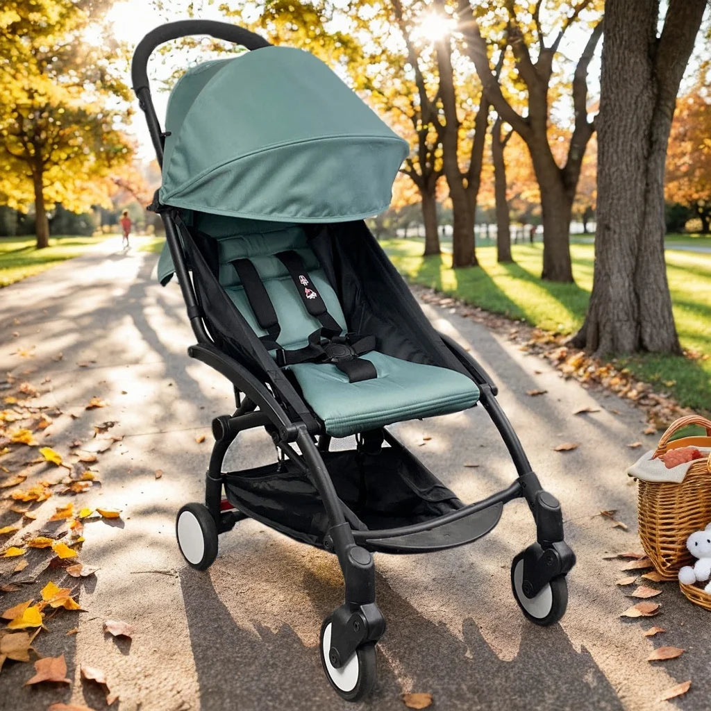 Green stroller on a path in a park with trees and leaves.