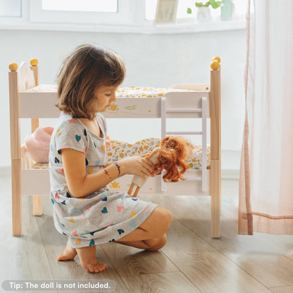 Child playing with a doll in a room with wooden furniture and white walls.